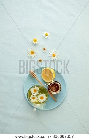 Chamomile Flowers And Chamomile Tea. Chamomile Tea In Glass Teacup With Flowers, Honey And Lemon, To
