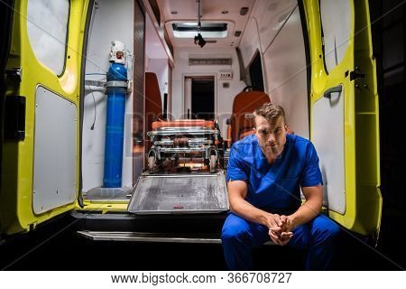 Serious Man In A Medical Iniform Sitting In The Back Of An Ambulance Car