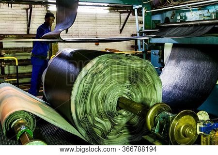 African Factory Worker Checking A Roll Of Rubber On A Machine In A Conveyor Belt Factory