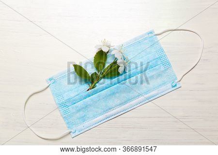 Medical Protective Mask And Buds Of White Flowers On A White Background With Copy Space. Medical Pro