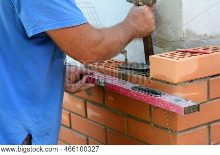 Bricklayer Using A Spirit Level To Check Bricklaying Wall Corner. Builder Contructor Laying Brick Wa