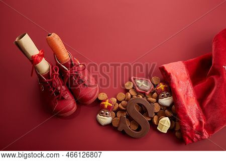 Saint Nicholas - Sinterklaas Day With Shoe, Carrot And Traditional Sweets On Red Background