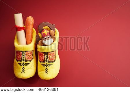 Saint Nicholas - Sinterklaas Day With Shoe, Carrot And Traditional Sweets On Red Background