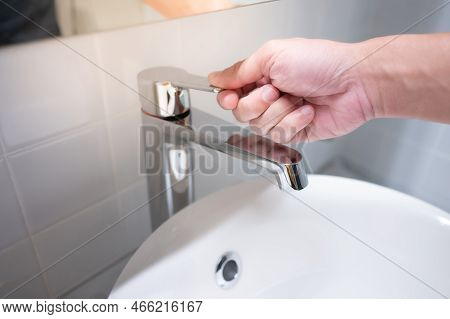 Male Hand Closing Water Tap Or Faucet In Bathroom. Save Water At Home Or Water Conservation Concepts
