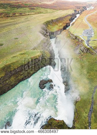 Vertical Photo Of Gullfoss Waterfall In Autumn Time Of The Year, Vibrant Green Hills Surrounding The