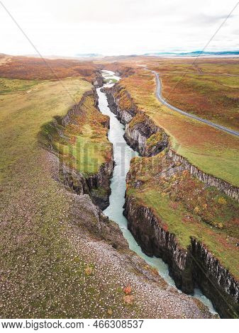 Vertical View Of A River Running In A Canyon, Vibrant Autumn Colors On The Hills Around It