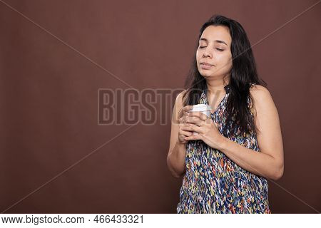 Relaxed Indian Woman Drinking Coffee To Go, Enjoying Hot Cappuccino With Closed Eyes. Person Holding
