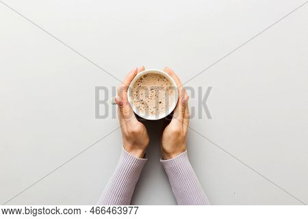 Minimalistic Style Woman Hand Holding A Cup Of Coffee On Colored Background. Flat Lay, Top View Capp