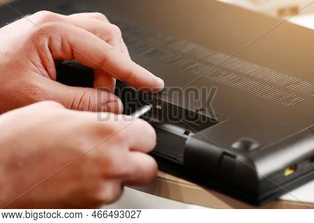 Repairman's Hands Unscrewing The Screws From The Laptop Case With A Screwdriver. Computer Service An
