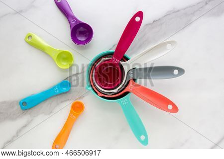 Set Of Measuring Spoons And Measuring Cup Made From Colorful Plastic Lay On Marble Background.