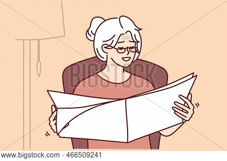 Elderly Woman Reads Newspaper With Latest News Or Announcements Sitting In Cozy Home Chair. Gray-hai