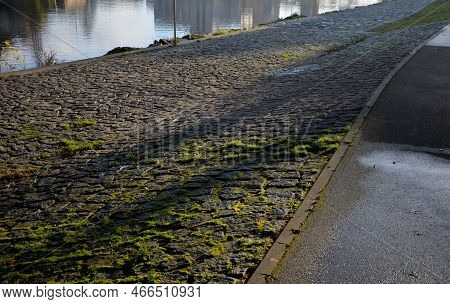 Edge Of The River Bank Reinforced With Giant Stones As A Breakwater Against Erosion Of Stone Paving 