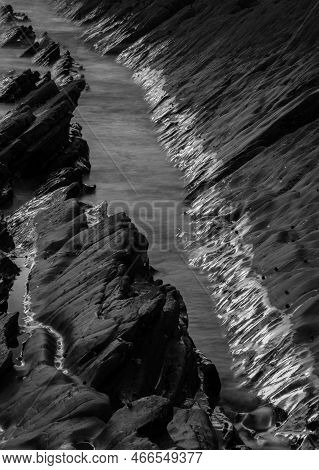 Abstract Landscape Image Of Rocks On Welcome Mouth Beach At Sunset With Tide Marks On Rocks Reflecti