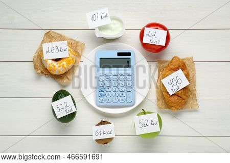 Calculator And Food Products With Calorific Value Tags On White Wooden Table, Flat Lay. Weight Loss 