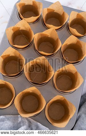 Scooping Dough Into The Cupcake Pan Lined With Parchment Muffin Liners To Bake Sharlotka Muffins.