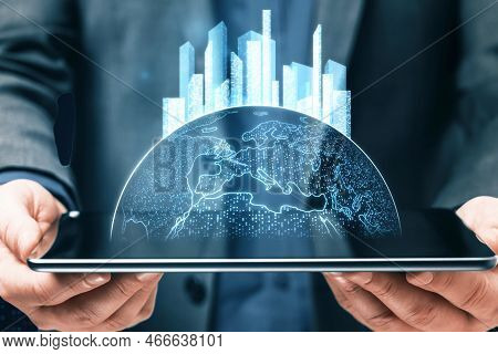 Close Up Of Male Hand Holding Tablet With Glowing Map With City Hologram On Blurry Background. Abstr