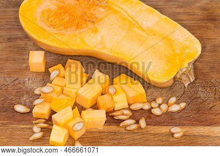 Diced Slices Of The Butternut Squash, Seeds And Half Of The Same Squash Cut Lengthwise On The Wooden