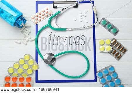 Clipboard With Word Herpes, Different Pills And Stethoscope On White Wooden Table, Flat Lay