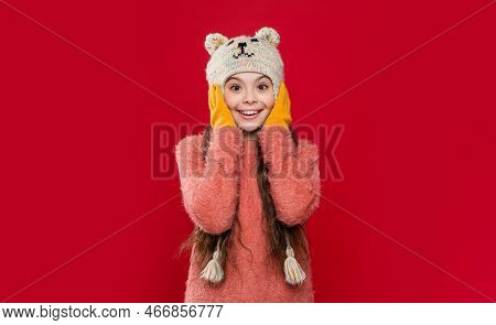 Teen Kid Model In Earflap Hat And Gloves. Teen Kid In Earflap Hat Isolated On Red Background.