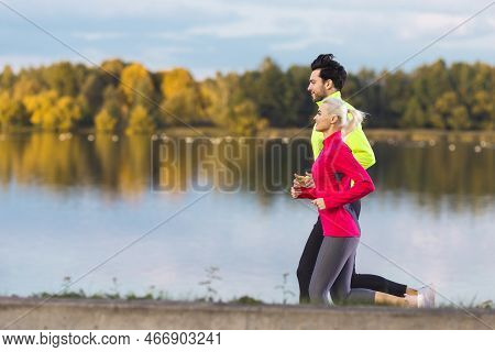 Jogging Concepts. Running Couple While Training Outdoors On Road At River For Durable Marathon Prett