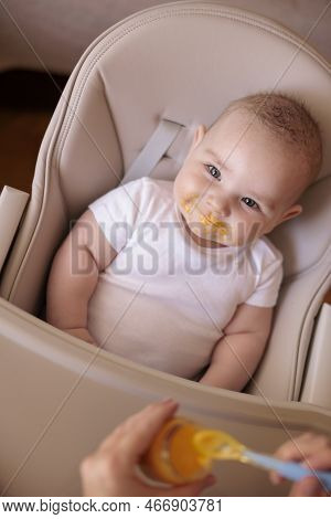 High Angle View Of Mother Feeding Cheerful Baby Boy With Porridge, Baby Sitting In High Chair All Me