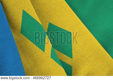 Saint Vincent And The Grenadines Flag With Big Folds Waving Close Up Under The Studio Light Indoors.
