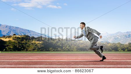 Young businessman in suit running on track
