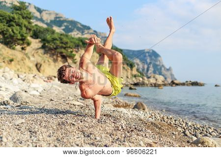 Happy guy on the beach holding a finger up in the unusual position