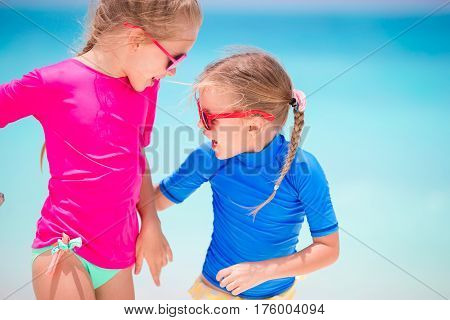 Adorable little girls have fun on white beach during vacation