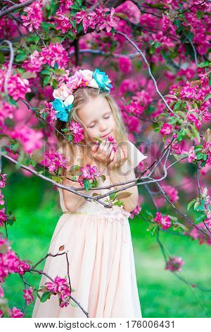 Adorable little girl in blooming apple garden on beautiful spring day