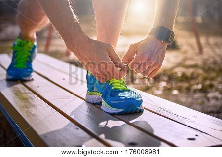Athlete during training tying shoelaces on sneakers summer.