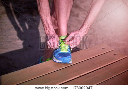 Athlete during training tying shoelaces on sneakers summer.