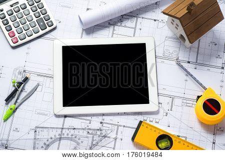 digital tablet with architectural blueprints rolls and tools