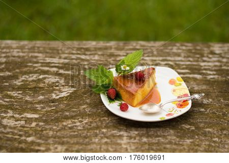 Delicious homemade Flan dessert or creme caramel dessert with mint. Slice of Milk Pudding over a wooden table. Brazilian Flan with strawberries. Panna cotta dessert with caramel sauce.