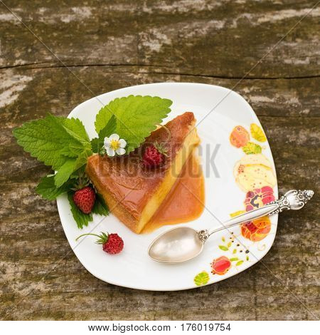 Delicious homemade Flan dessert or creme caramel dessert with mint. Slice of Milk Pudding over a wooden table. Brazilian Flan with strawberries. Panna cotta dessert with caramel sauce.