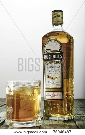 Bushmills Whiskey Glass And Bottle On Green Wooden Table