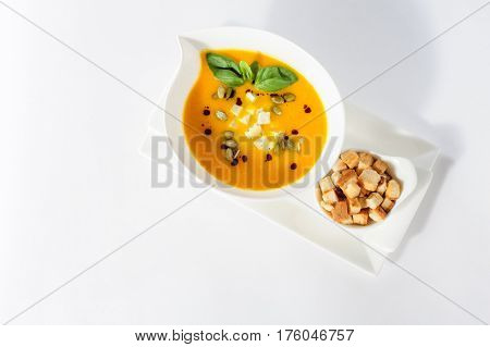 Roasted pumpkin soup with cream and pumpkin seeds on white background. Lot of copy space