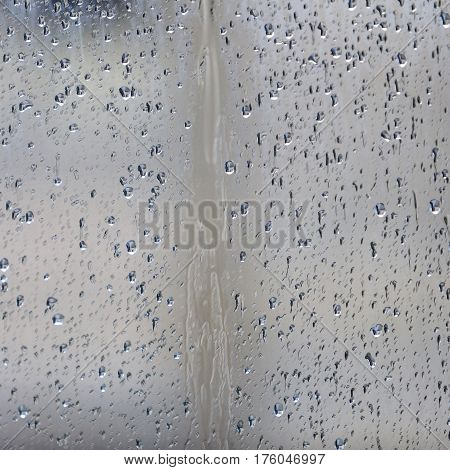 glass pane with raindrops and water during rain storm