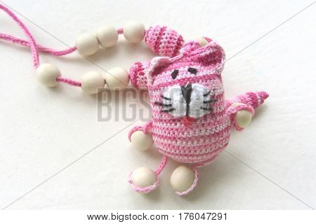 Knitted pink striped handmade crafted cat. Children's toy. Crochet pattern. Handicraft manufacturing.
