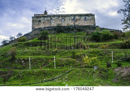 Side view on medieval monastery on the hill surrounded by old stone wall