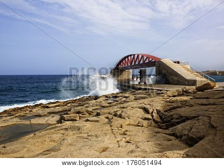Lighthouse and Grand Harbour Bridge in Valletta with wavy blue sea and big clouds formation background, dramatic sea view with lighthouse and Grand Harbour Bridge in Valletta,Malta