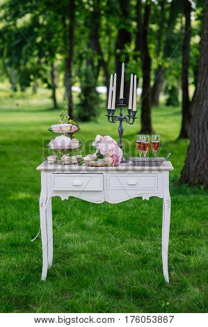 Wedding decorations. Wedding bouquet on vintage background in the park. Glasses with champagne and a candlestick