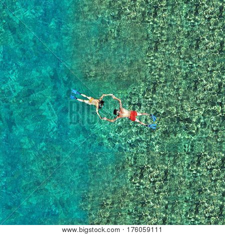 Snorkeling couple in crystal clean sea water. View from a drone