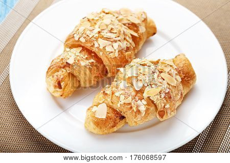 Traditional French breakfast croissant with almonds on a platel on a napkin