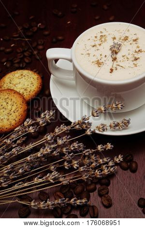 Cup of coffee with milk pussy-willow and dried branches and leaves at white background. Cake on desk