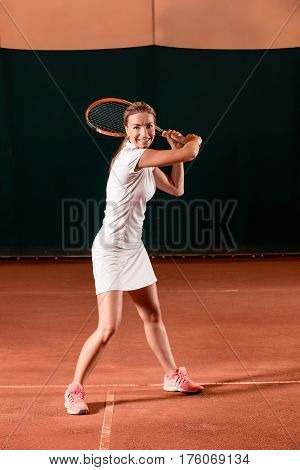 Sportswoman at the tennis court with racquet. Indoor tennis court