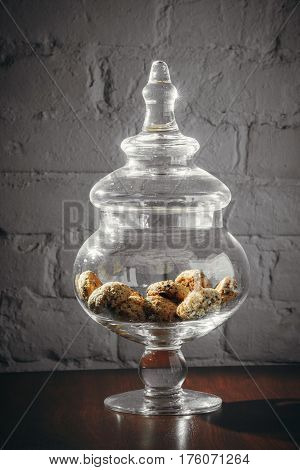 glass vase with cookies and cover on desk near grey wall. Kitchen