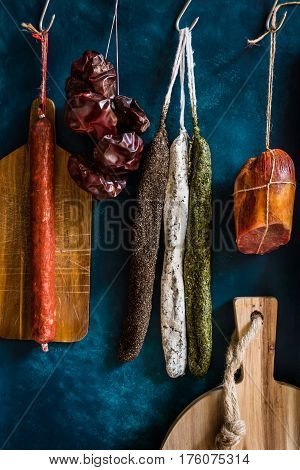 Assortment of sausages Spanish charcuterie wood cutting board dry peppers on dark blue background gourmet rustic style
