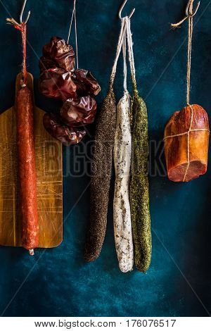Assortment of sausages Spanish charcuterie wood cutting board string with dry peppers on dark blue background gourmet rustic pantry