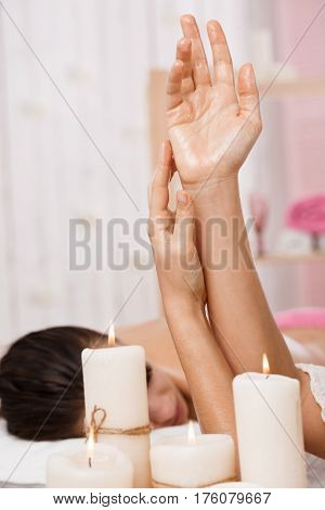 Closeup of female hands applying moisturizing lotion and oil before doing spine massage on woman